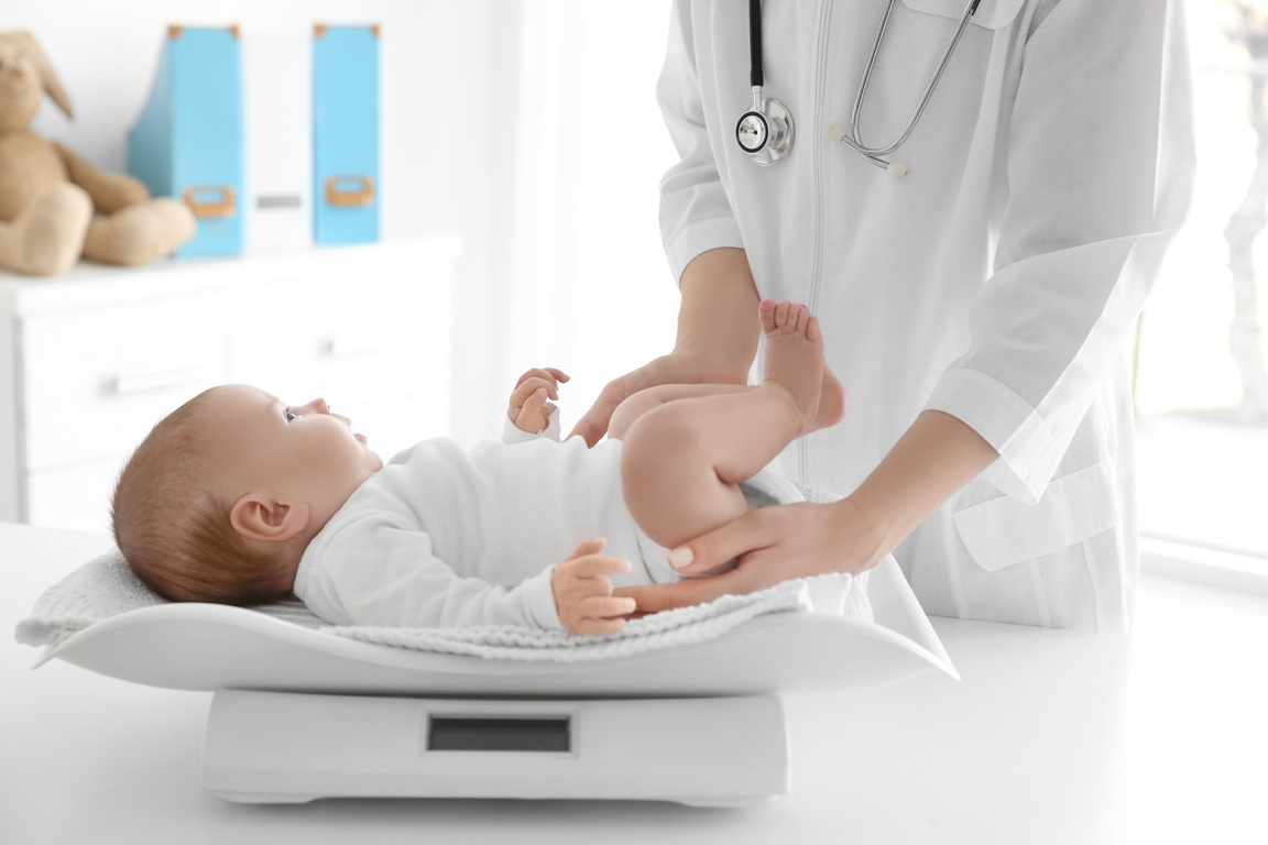 Doctor Weighing Baby in Clinic